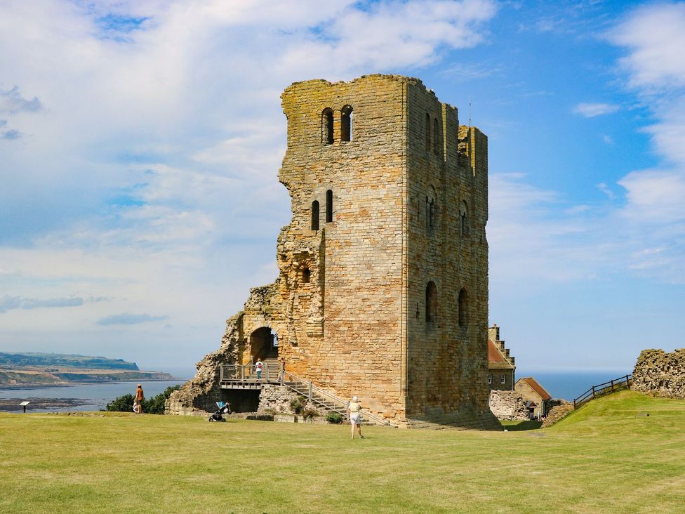 A castle ruin near the ocean with grass and a blue sky at The Lookout 