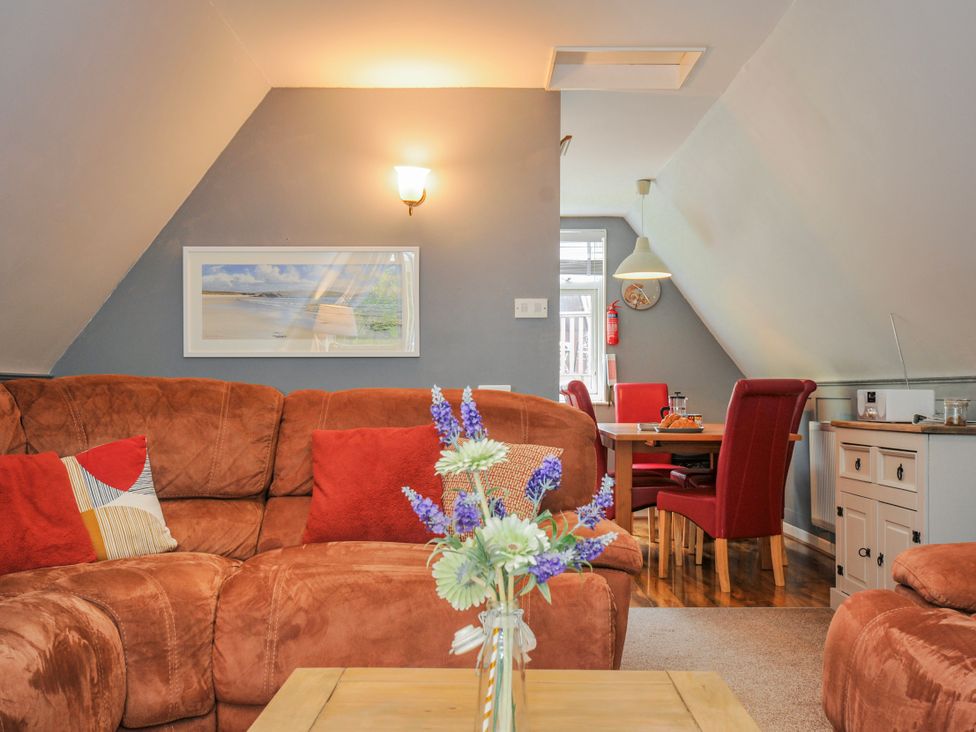 A living room with a sofa and dining area at Hideaway Cottage in St Ann's Chapel, Cornwall