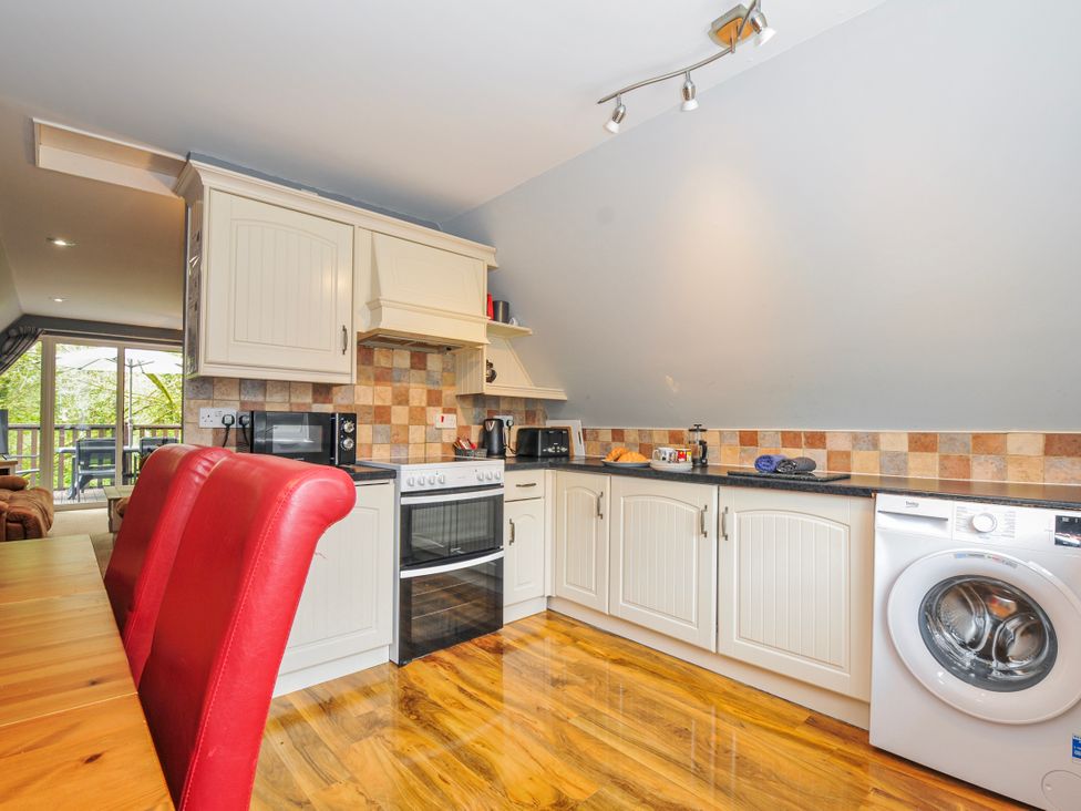 A kitchen with appliances and seating at Hideaway Cottage St Ann's Chapel, Cornwall