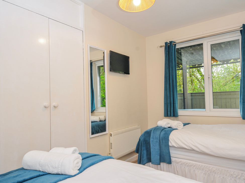 A bedroom with two beds and a television at Hideaway Cottage, St Ann's Chapel, Cornwall