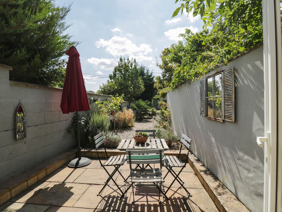 A garden with a table and chairs under an umbrella at Mallards in Bourton-On-The-Water