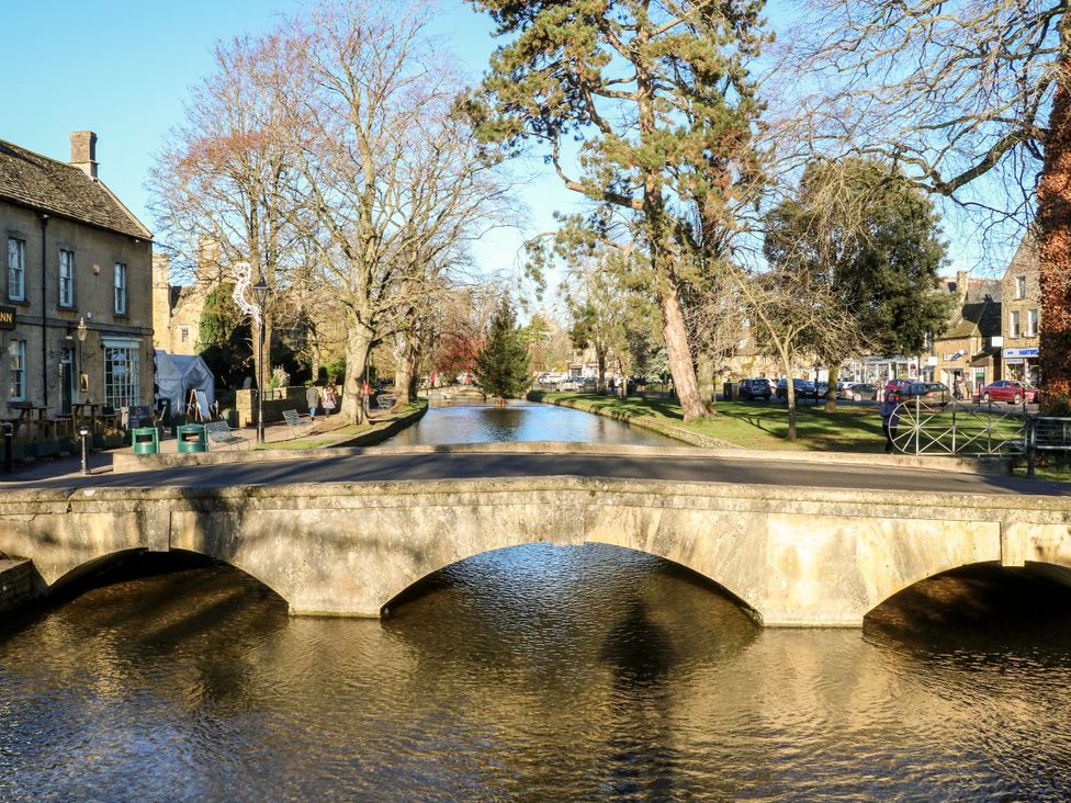 A bridge over a river with trees and buildings at Mallards in Bourton-On-The-Water