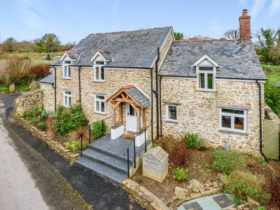 A house with stone walls and a front porch at Middle Dean Farmhouse in Trentishoe near Parracombe