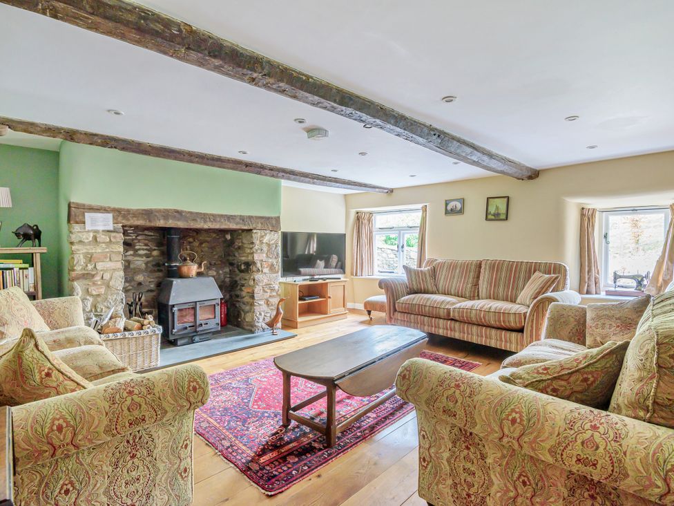 A living room with a fireplace and sofa at Middle Dean Farmhouse Trentishoe near Parracombe