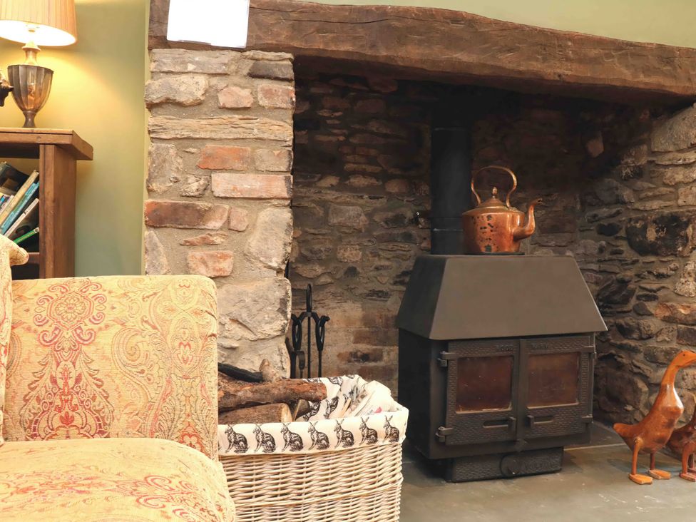 A living room with a fireplace and a sofa at Middle Dean Farmhouse in Trentishoe near Parracombe