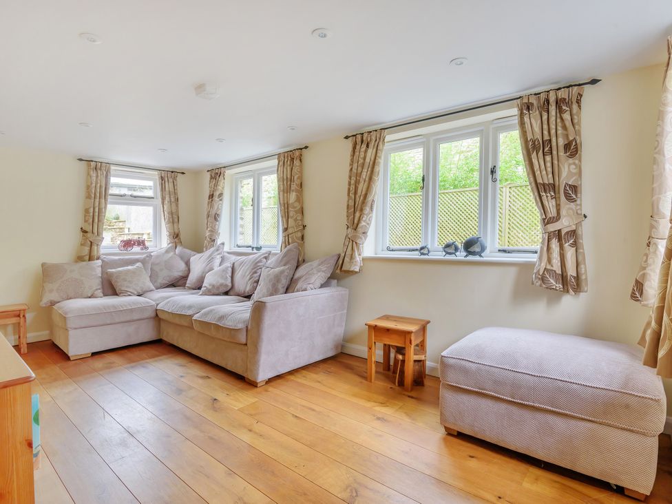 A living room with a sofa and windows at Middle Dean Farmhouse in Trentishoe near Parracombe