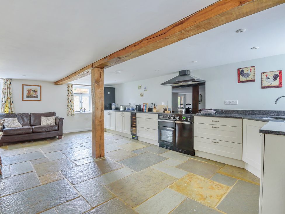 A kitchen with cabinets and a sofa at Middle Dean Farmhouse near Trentishoe