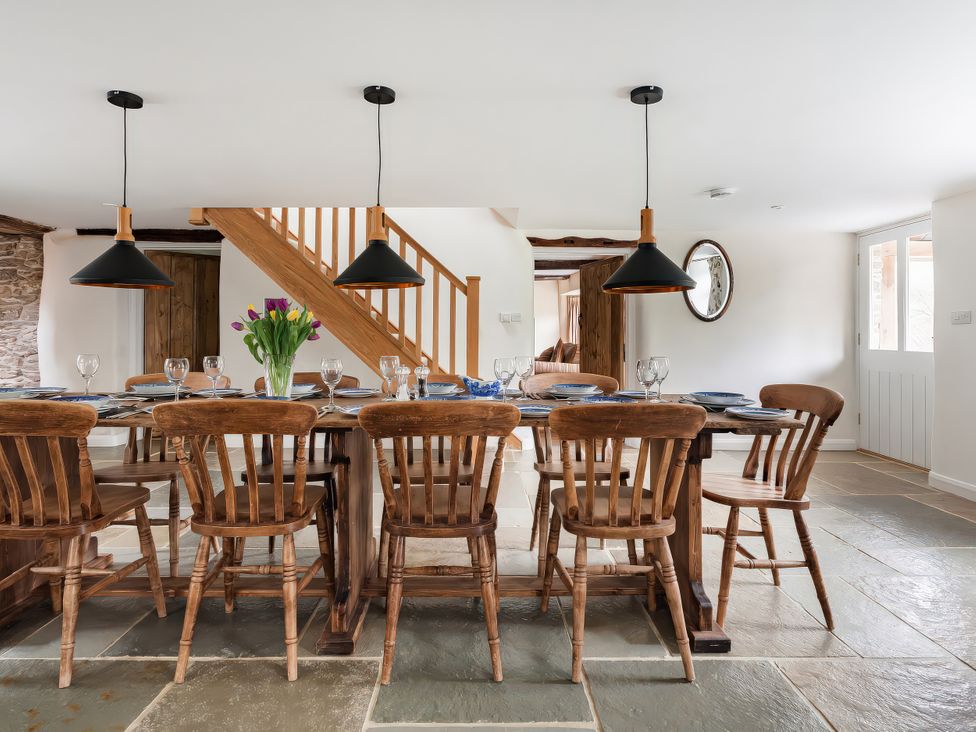 A dining room with a long table and chairs at Middle Dean Farmhouse in Trentishoe near Parracombe