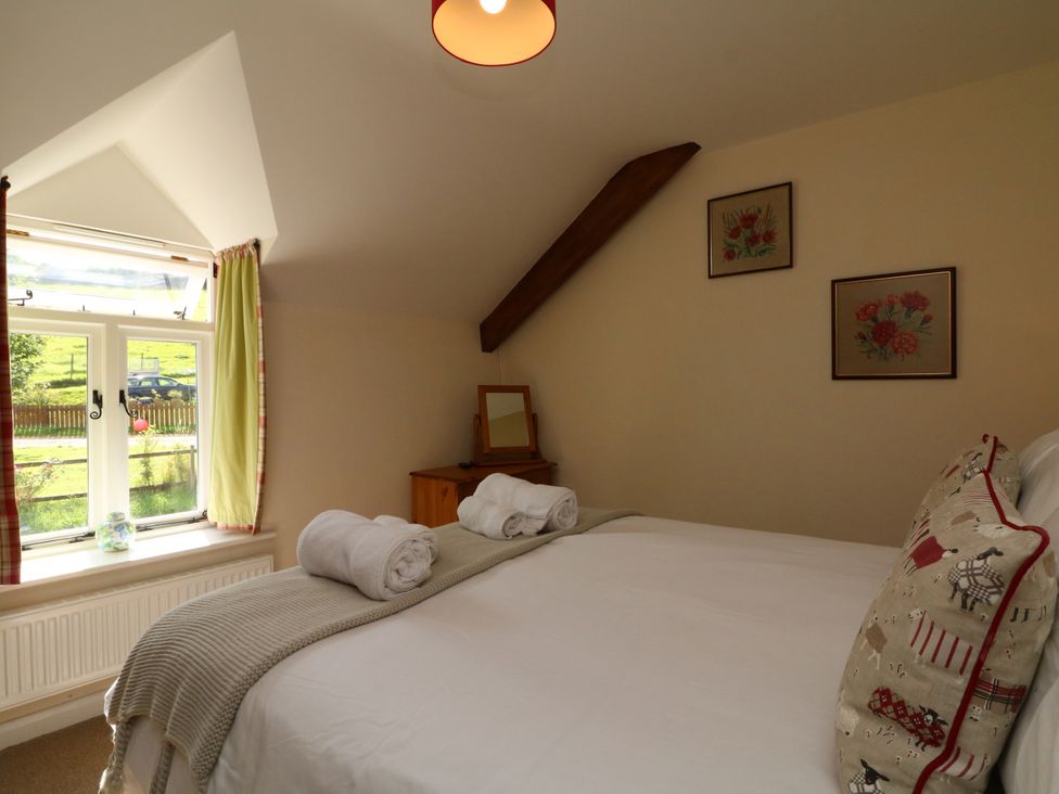 A bedroom with a bed and dresser at Middle Dean Farmhouse, Trentishoe near Parracombe