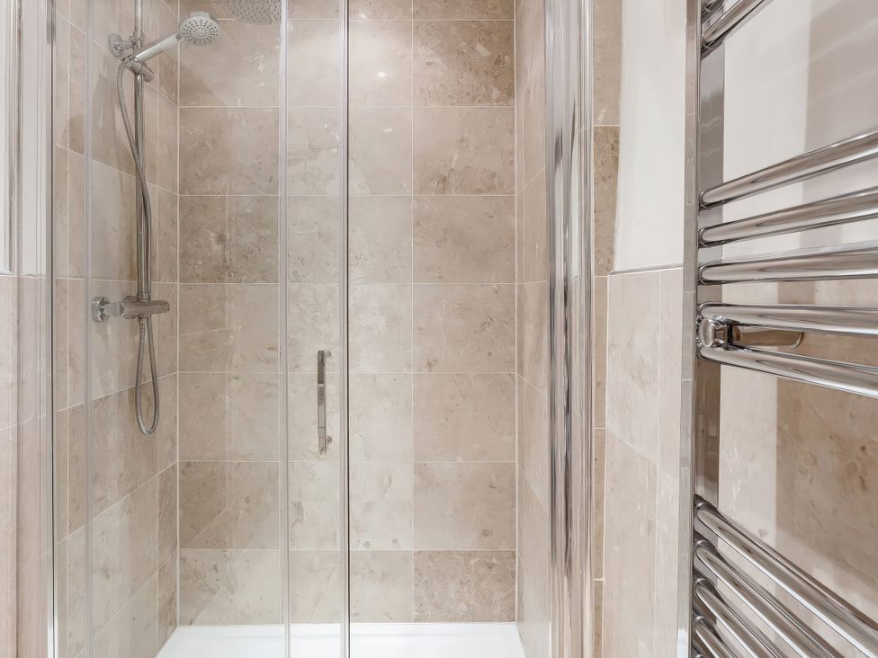 A shower with glass enclosure and towel rail at Middle Dean Farmhouse Trentishoe near Parracombe