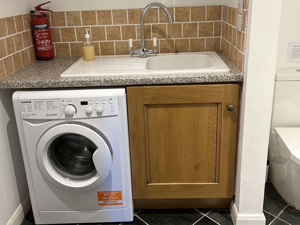 A laundry room with a washing machine and sink at Middle Dean Farmhouse Trentishoe near Parracombe