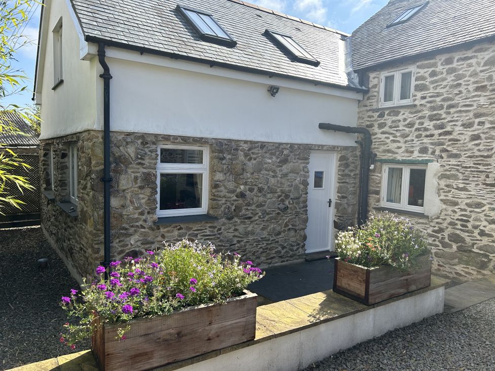 A house with a stone exterior and flowers in planters at Middle Dean Farmhouse, Trentishoe near Parracombe