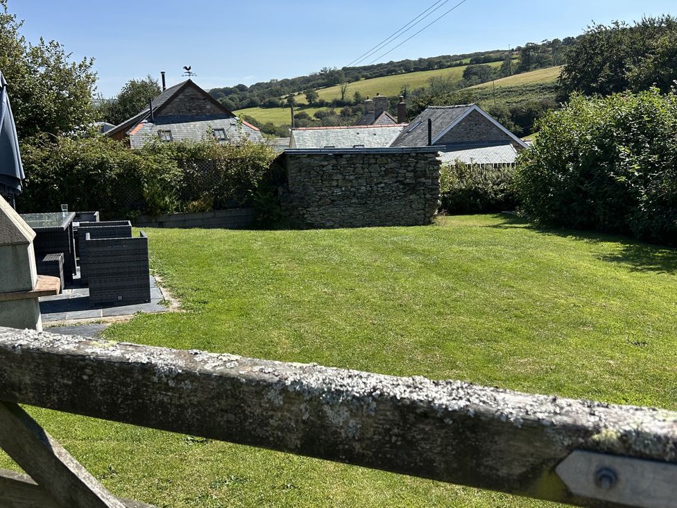 A garden with a stone wall and patio furniture at Middle Dean Farmhouse Trentishoe near Parracombe