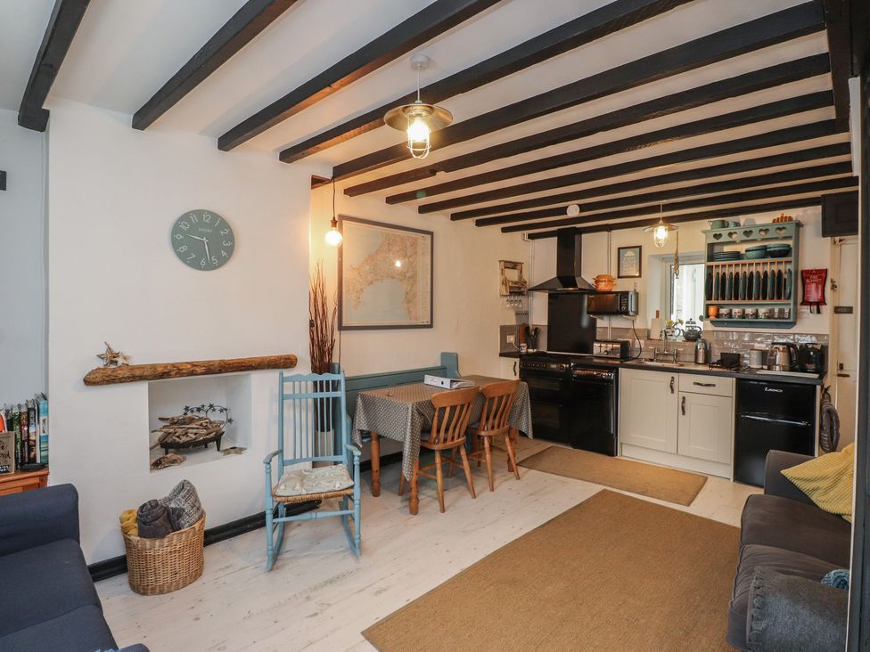 A living room with a dining area and kitchen appliances at Menuchah in Criccieth