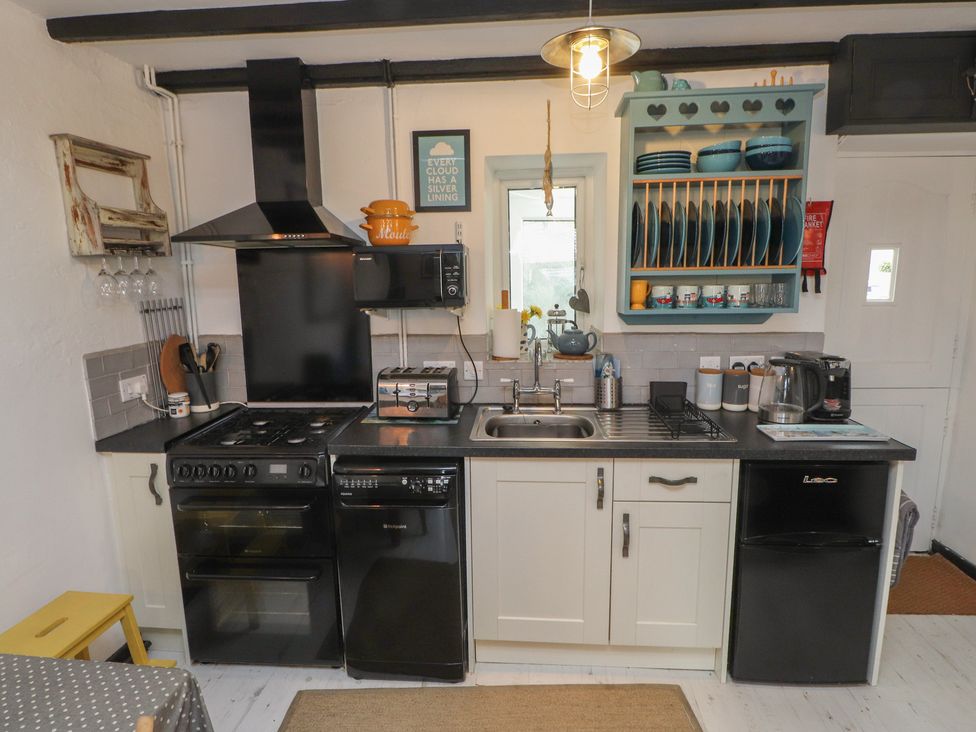 A kitchen with appliances and dishes in cabinets at Menuchah in Criccieth