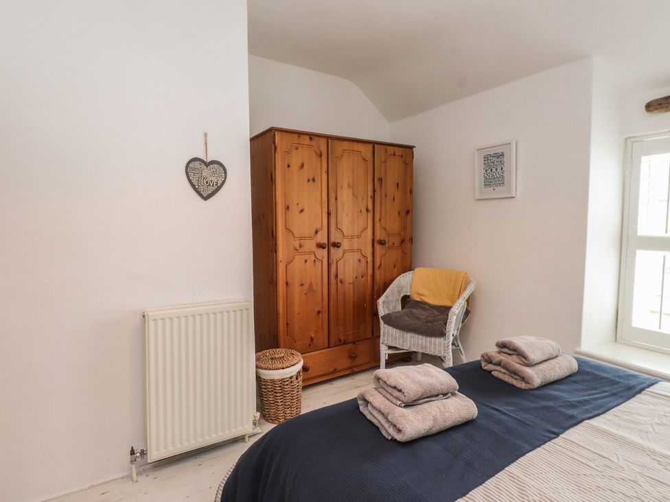 A bedroom with a wardrobe and towels folded on the bed at Menuchah in Criccieth