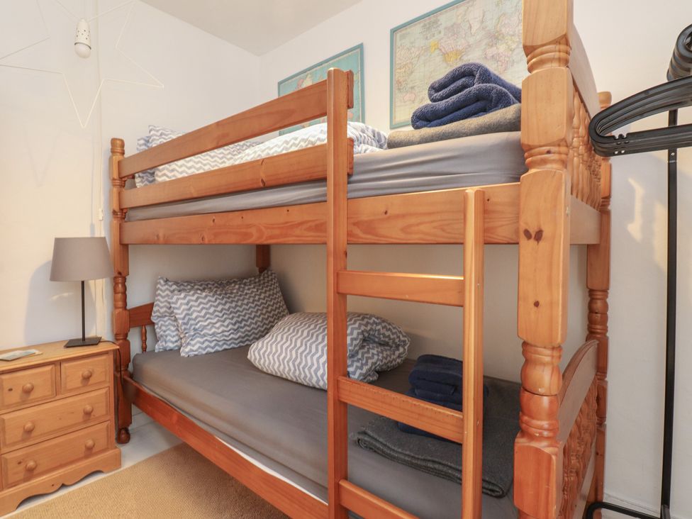 A bedroom with a bunk bed and bedside lamp at Menuchah in Criccieth