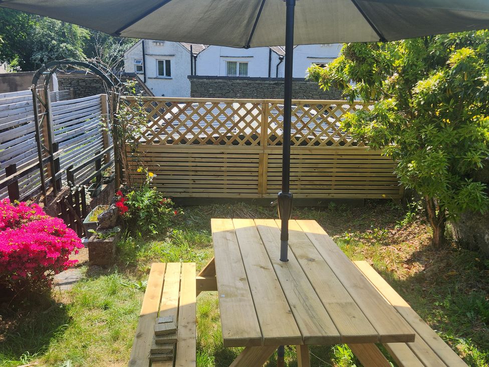 A garden with a wooden table and umbrella at 1A Lower Croft Street Settle
