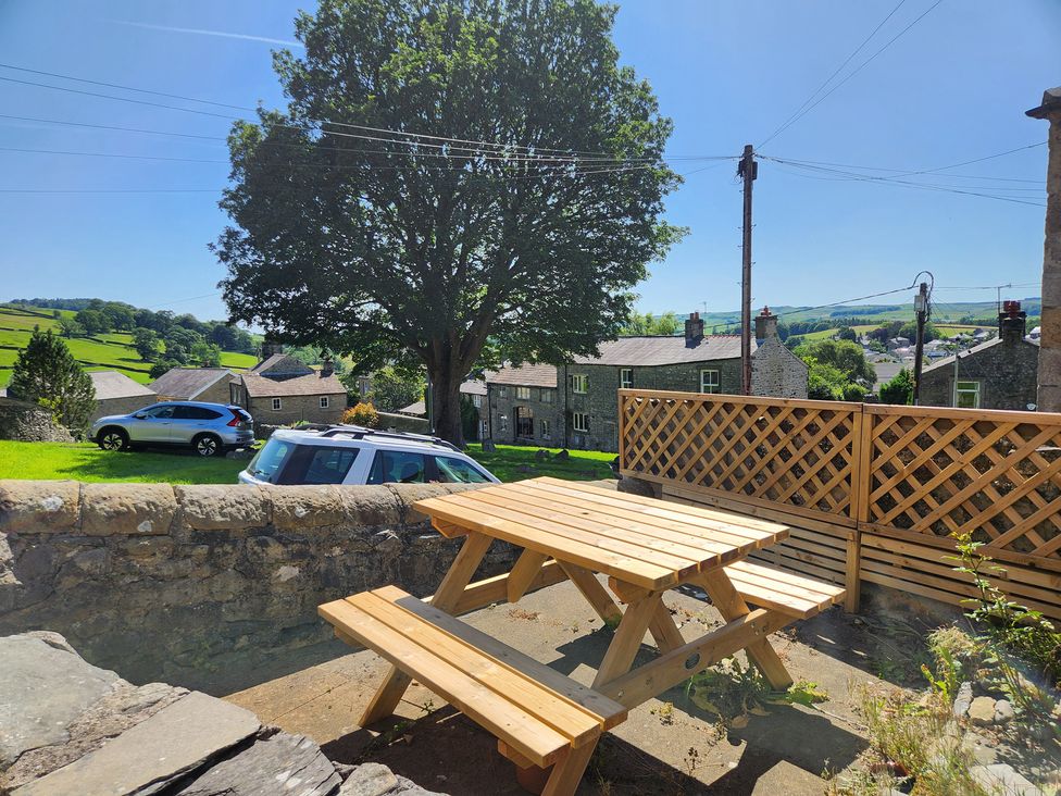 An outdoor seating area with a table and benches at 1A Lower Croft Street Settle