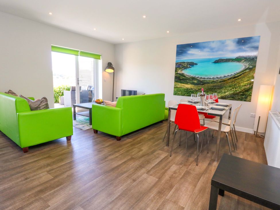 A living room with green sofas and a dining area at Overcombe Mill Nottington near Weymouth
