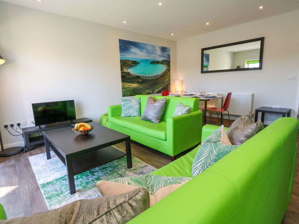 A living room with green sofas and a television at Overcombe Mill Nottington near Weymouth