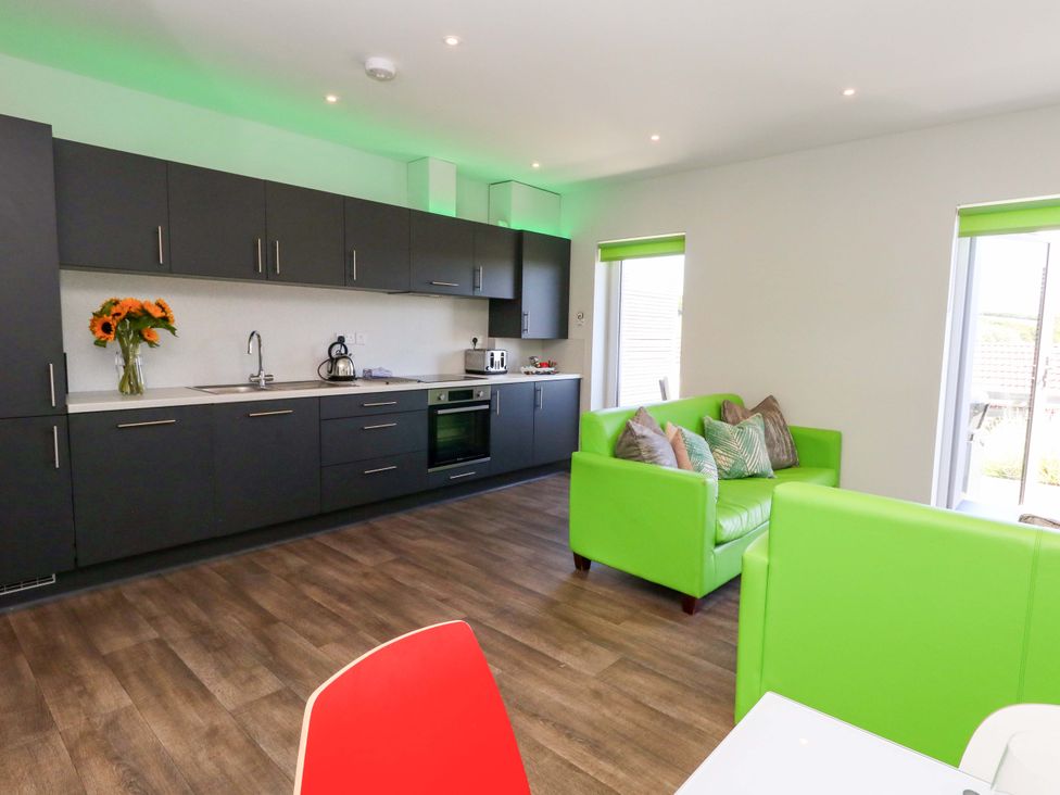 A kitchen with cabinets and a green sofa at Overcombe Mill in Nottington near Weymouth