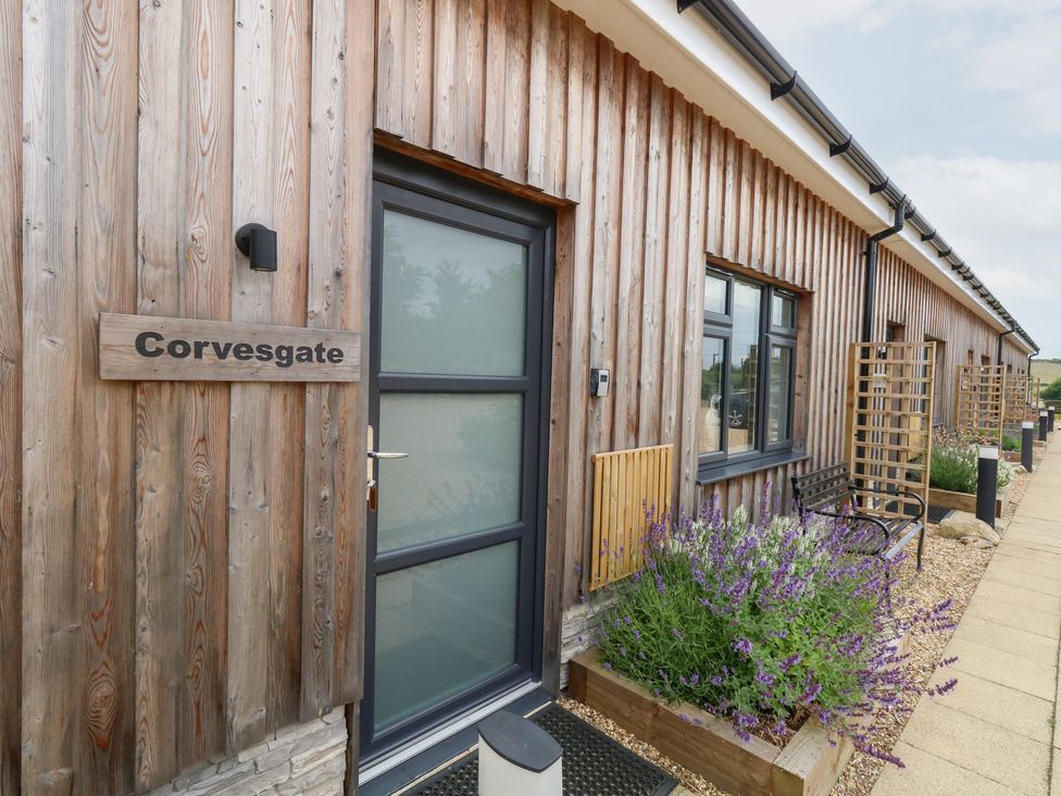 An outdoor entry area with a wooden exterior and a plant bed at Corvesgate in Nottington near Weymouth