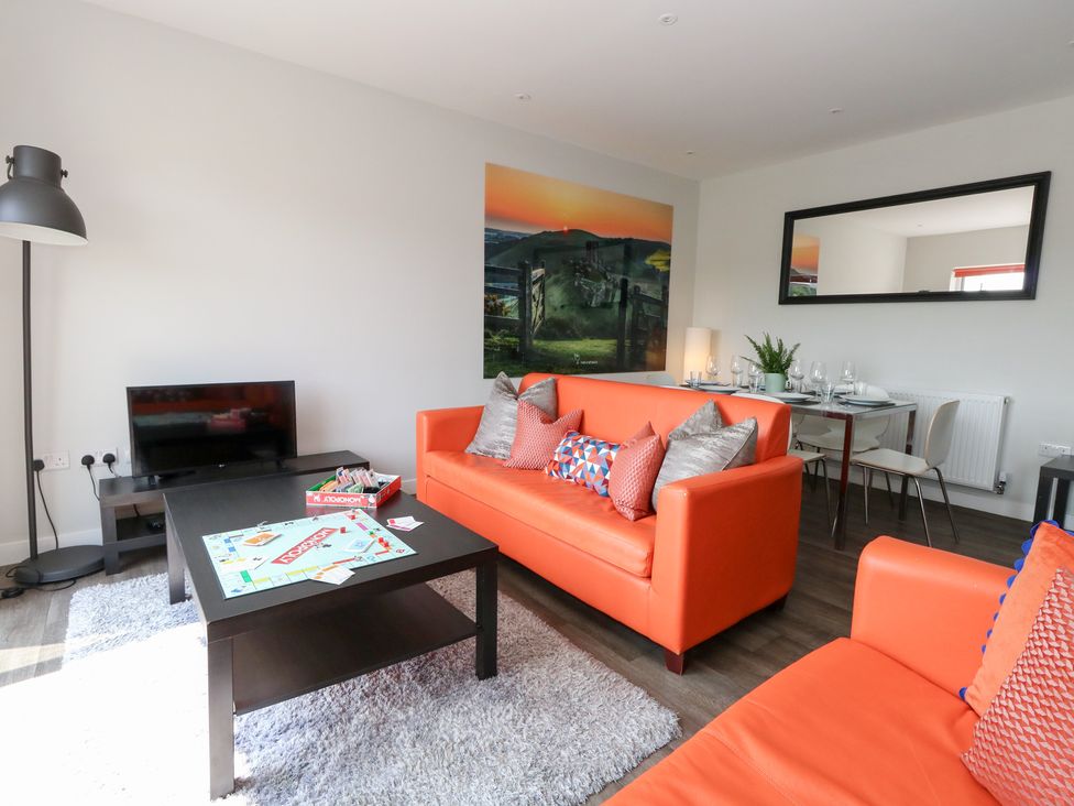 A living room with sofas, a coffee table, and a dining area at Corvesgate in Nottington near Weymouth