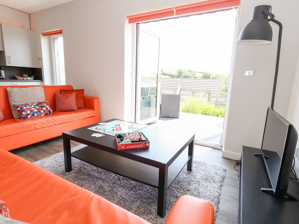 A living room with an orange sofa and coffee table at Corvesgate Nottington near Weymouth