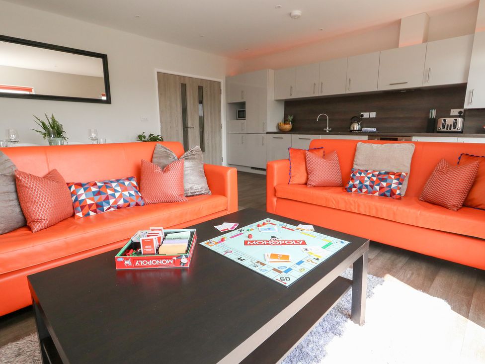 A living room with orange sofas and a monopoly game at Corvesgate Nottington near Weymouth