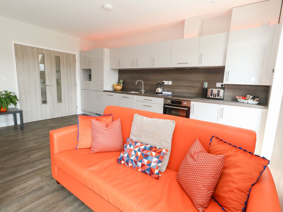 A living room with a sofa and kitchen area at Corvesgate in Nottington near Weymouth