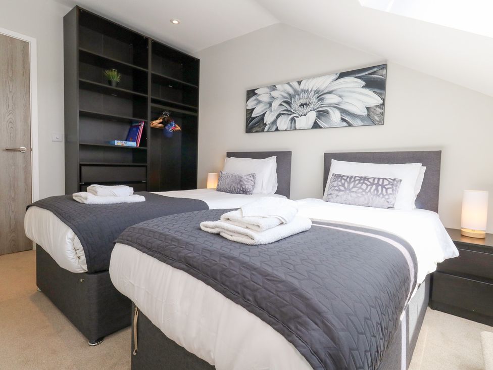 A bedroom with twin beds and shelving at Corvesgate in Nottington near Weymouth