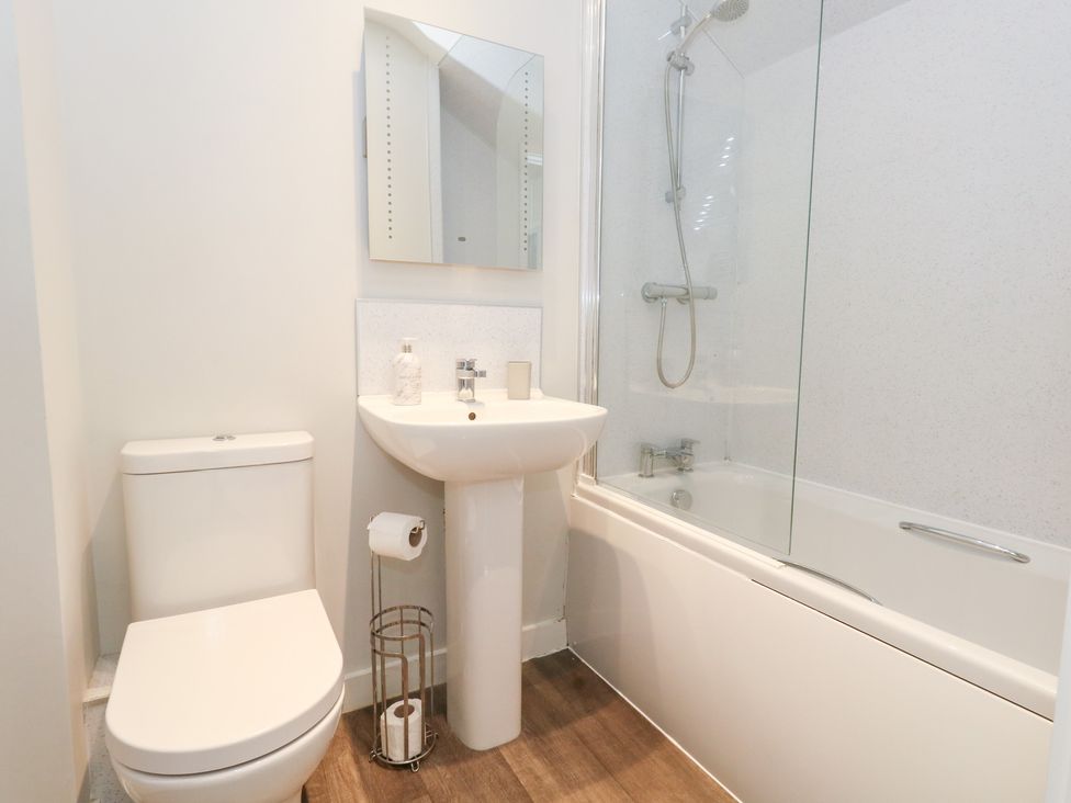 A bathroom with a toilet and sink next to a bathtub with a shower at Corvesgate in Nottington near Weymouth