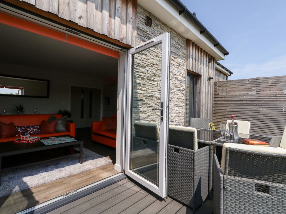 A living room with an orange sofa and glass table at Corvesgate Nottington near Weymouth