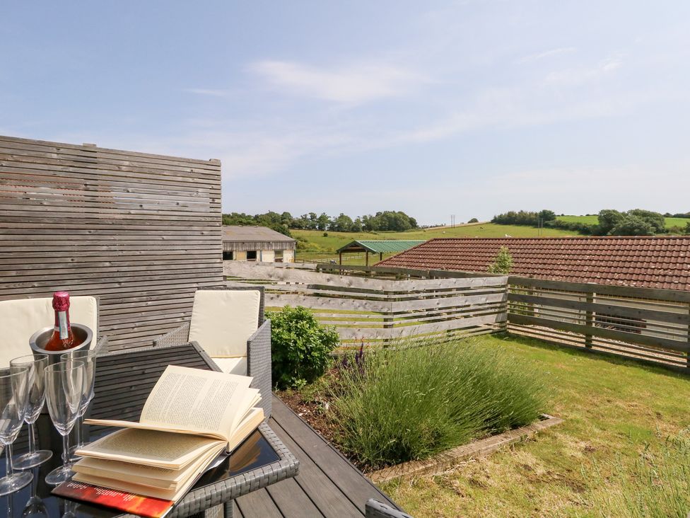 An outdoor seating area with a bottle and glasses at Corvesgate in Nottington near Weymouth
