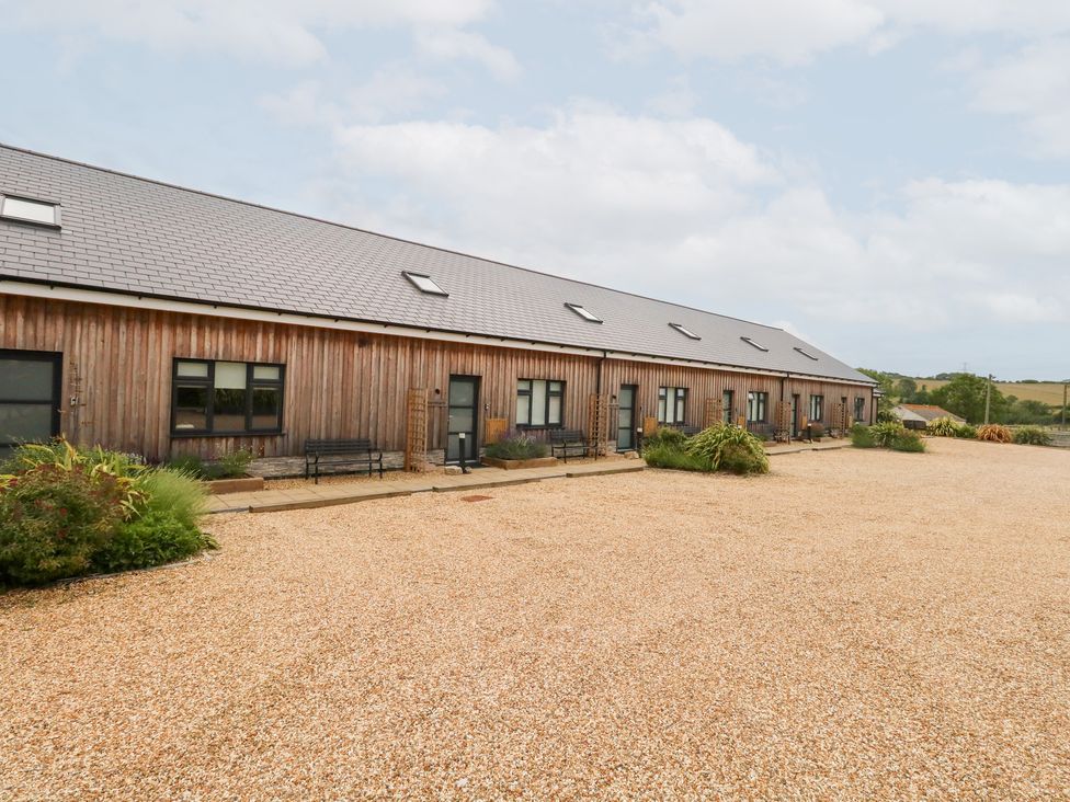 An outdoor view of a wooden building with gravel pathway at Corvesgate Nottington near Weymouth