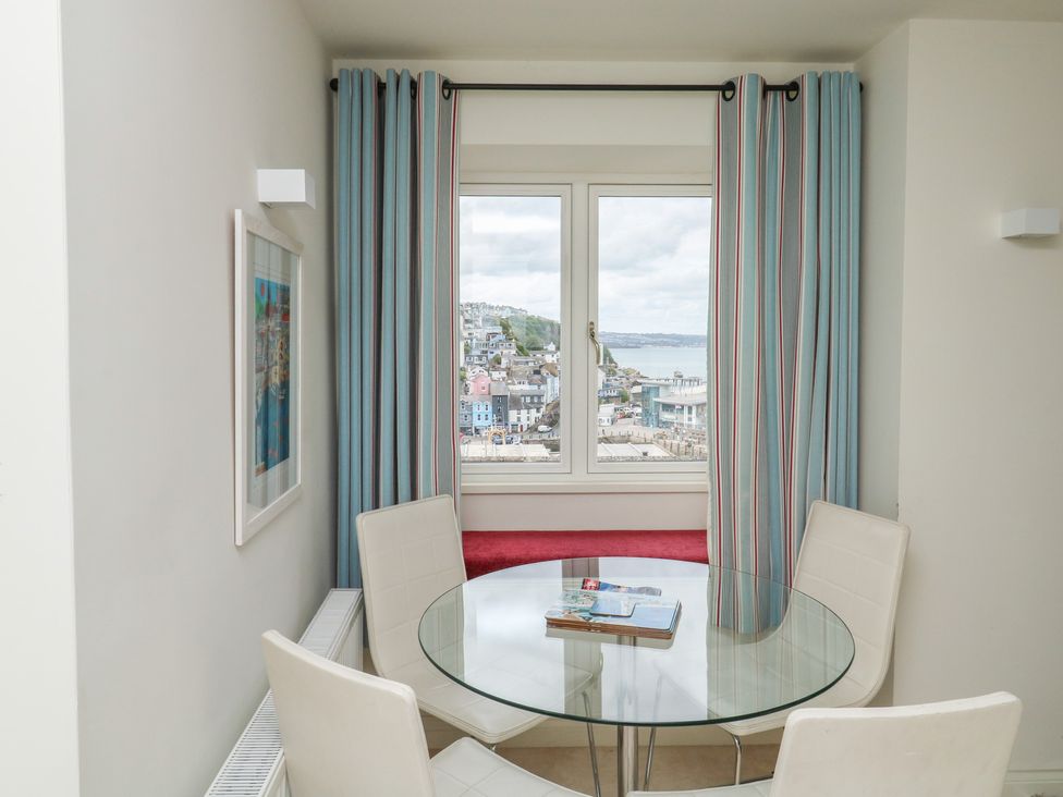 A dining room with a round table and a window view at Bay View in Brixham