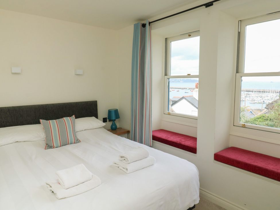 A bedroom with a bed and windows at Bay View in Brixham