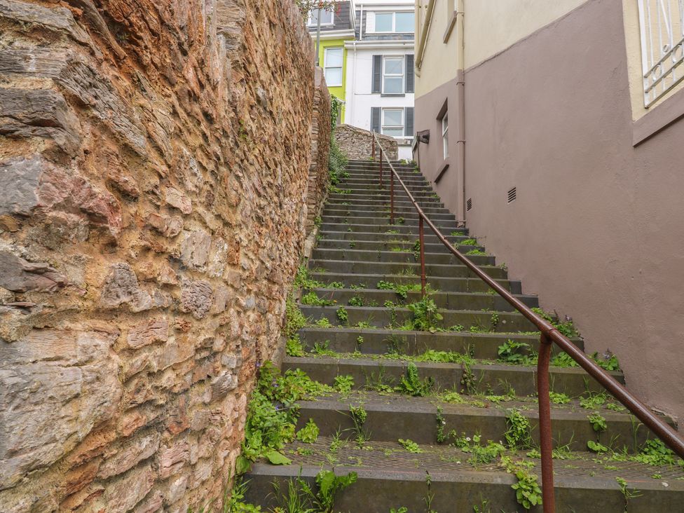 A set of stairs with a stone wall and plants at Bay View in Brixham