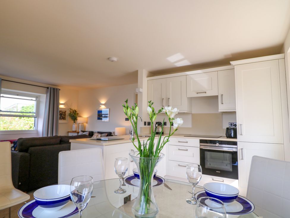 A dining room with a table set and kitchen appliances at Bay View in Brixham