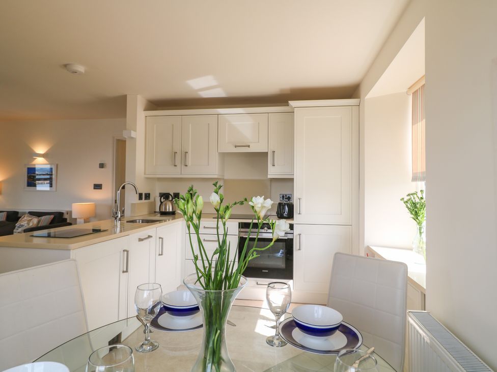 A kitchen with dining table and flowers at Bay View in Brixham