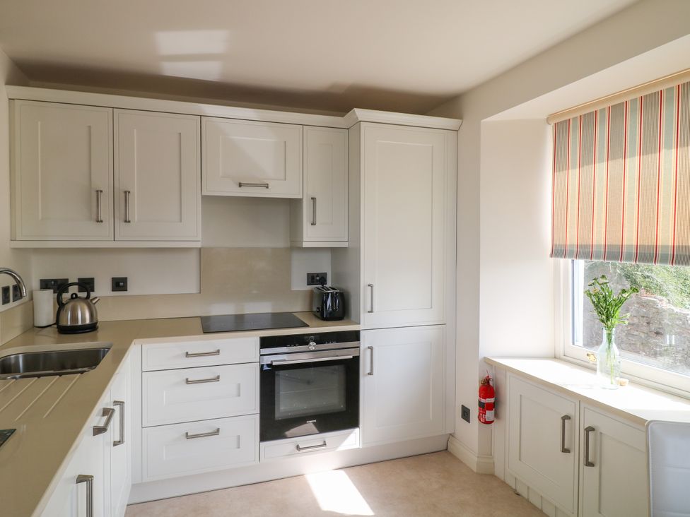 A kitchen with cabinets, kettle, and flowers at Bay View in Brixham