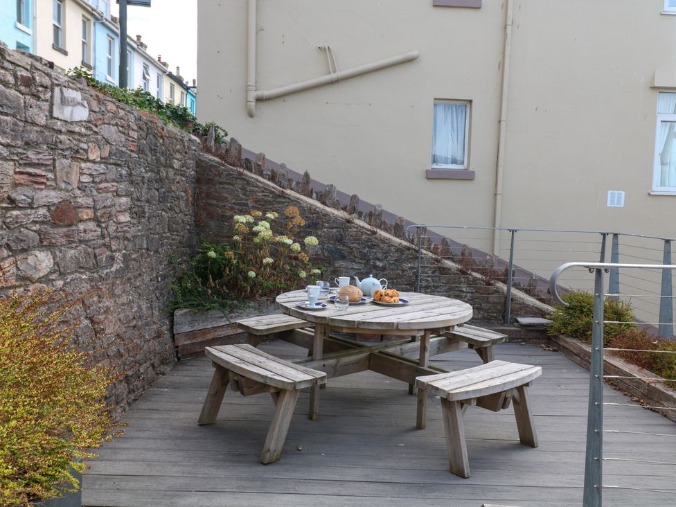 An outdoor dining area with a wooden table and chairs at Bay View in Brixham