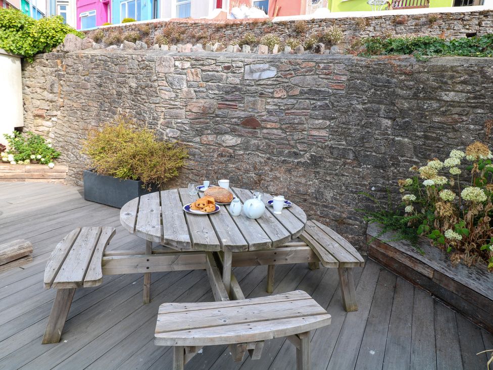 A garden with a wooden table and tea set at Bay View in Brixham
