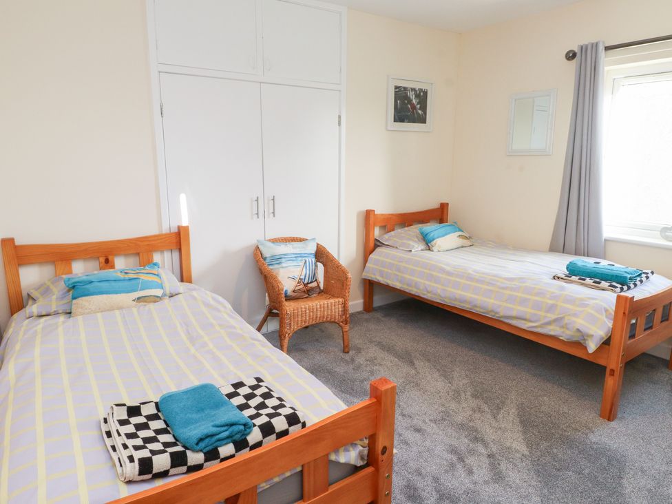 A bedroom with two beds and a chair at Glan Aber in Pwllheli