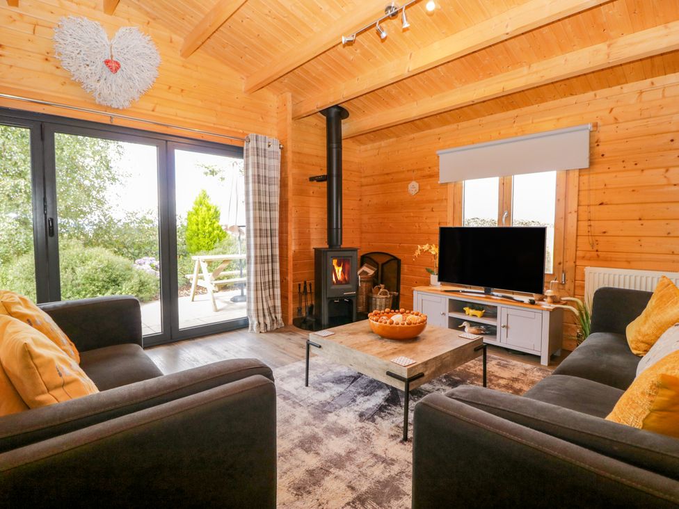 A living room with a wood stove and television at Howgills Retreat in Gatebeck near Kirkby Lonsdale