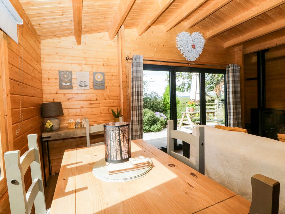 A dining area with wooden furniture and views to the outdoor space at Howgills Retreat Gatebeck near Kirkby Lonsdale