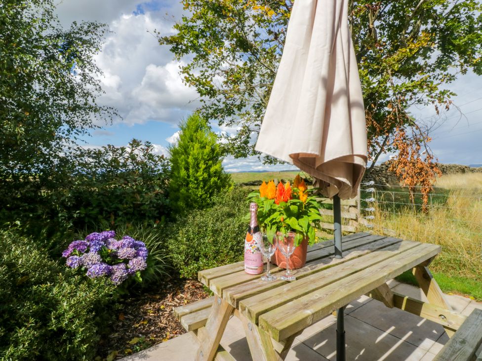 A table with flowers and a bottle at Howgills Retreat Gatebeck near Kirkby Lonsdale