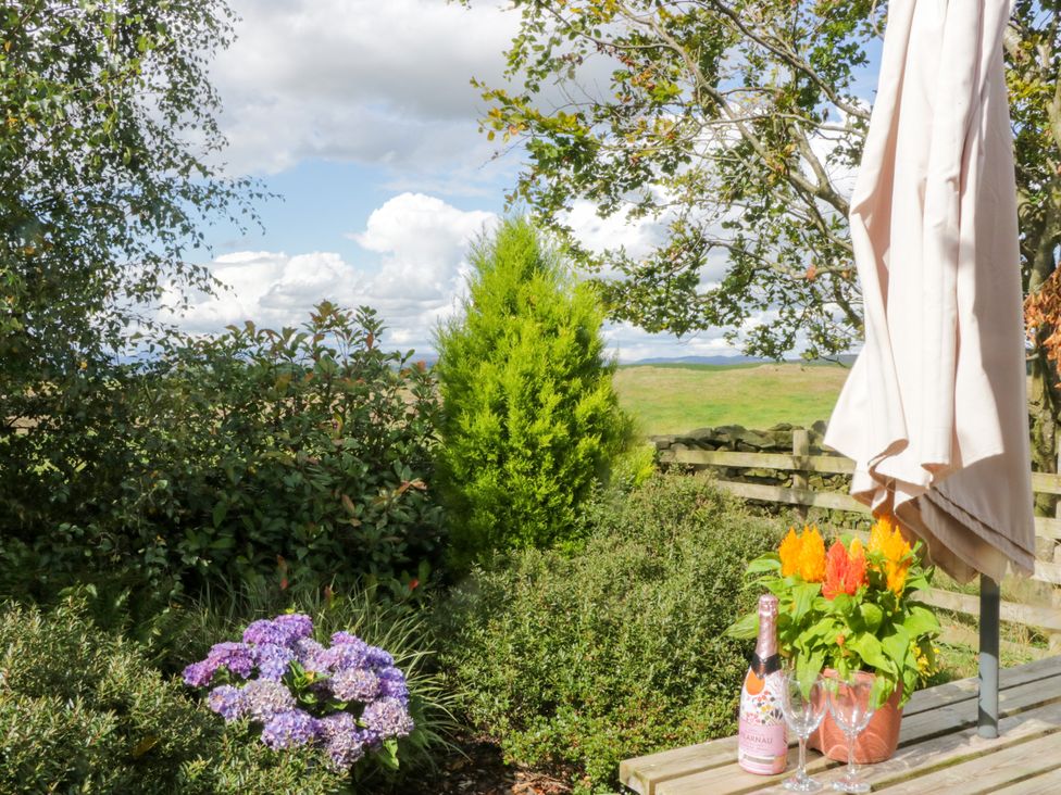 A table with a bottle and glasses surrounded by flowers at Howgills Retreat Gatebeck near Kirkby Lonsdale