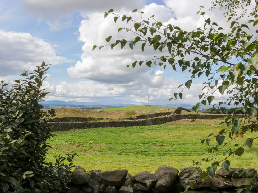 A view of a grassy area with a stone wall under cloudy sky at Howgills Retreat Gatebeck near Kirkby Lonsdale
